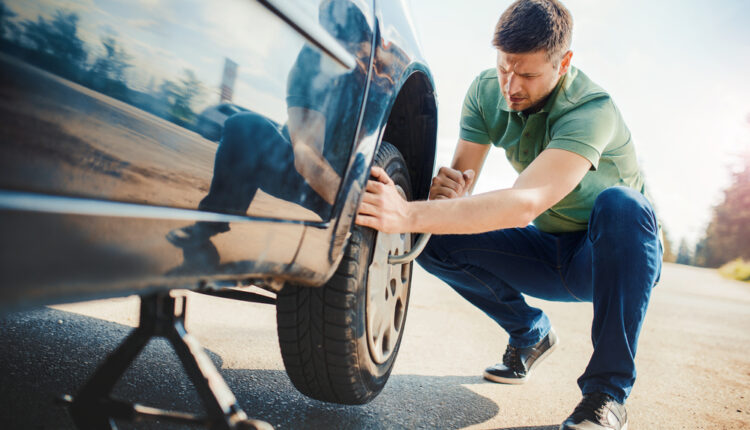 Man checking car tire condition before replacement in the UAE.