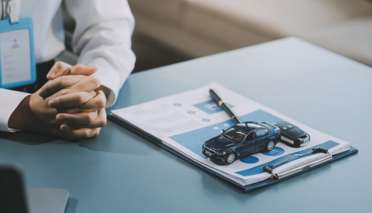 Car leasing paperwork with toy car, key, and pen on desk