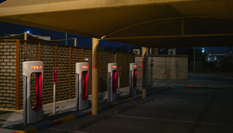 Tesla Superchargers in UAE at night under shaded parking, symbolizing battery durability in hot climates
