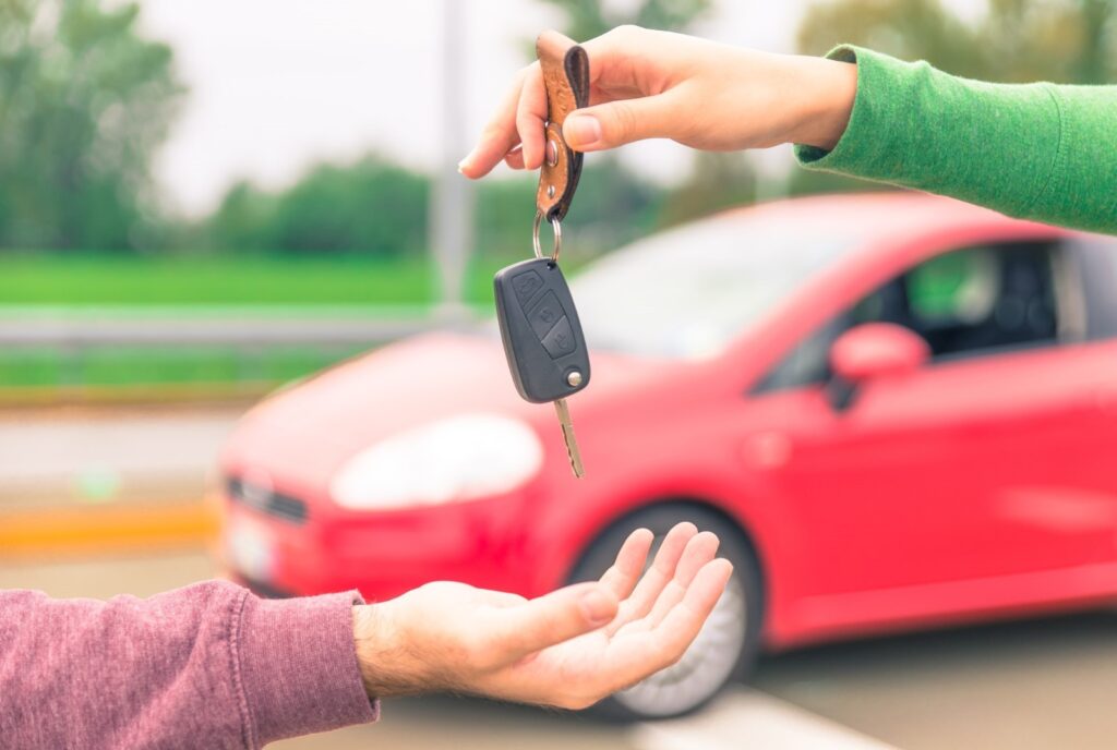 “Car owner handing keys to buyer with Dubai skyline in the background – selling cars in UAE 2025.