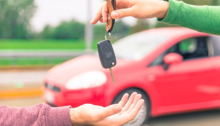 “Car owner handing keys to buyer with Dubai skyline in the background – selling cars in UAE 2025.