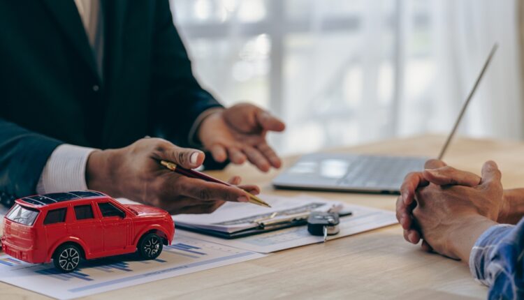 Seller discussing car sale with buyer, showing documents and the vehicle.
