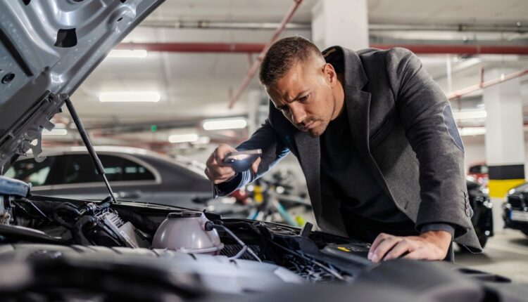 Mechanic inspecting a Hyundai Elantra engine in a garage using a flashlight