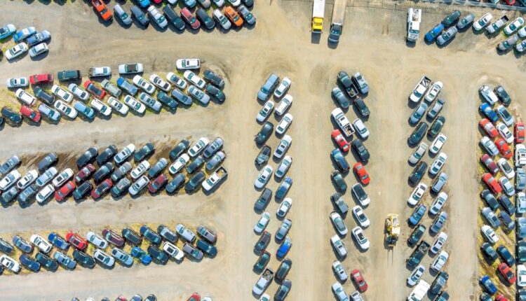 Rows of used cars at Al Aweer Auto Market in Dubai with showrooms on both sides and steady buyer traffic.