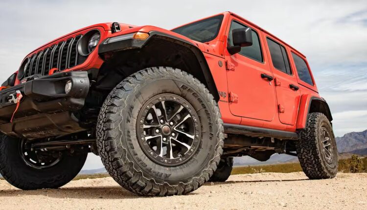 Jeep Wrangler off-roading across UAE desert dunes, kicking up sand.