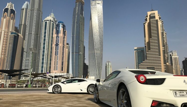 New cars parked against Dubai's iconic skyline, symbolizing the choice for first-time buyers in the UAE between new and used vehicles.