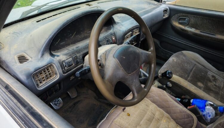 Dusty car interior filled with sand on dashboard, seats, and floor in UAE desert conditions