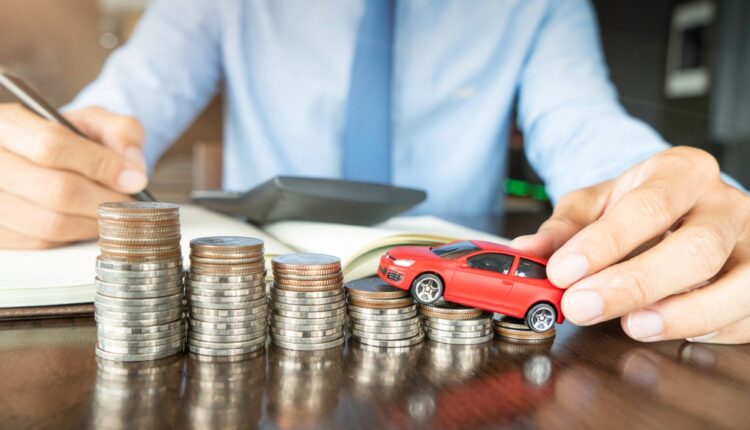 A person analyzing car ownership costs with toy car and stacked coins, representing depreciation and resale value.