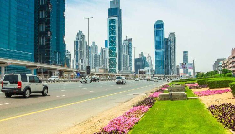 A wide-angle view of Sheikh Khalifa Bin Zayed Road showing orange traffic cones, digital lane closure signs, and traffic being diverted near construction barriers under a clear sky.