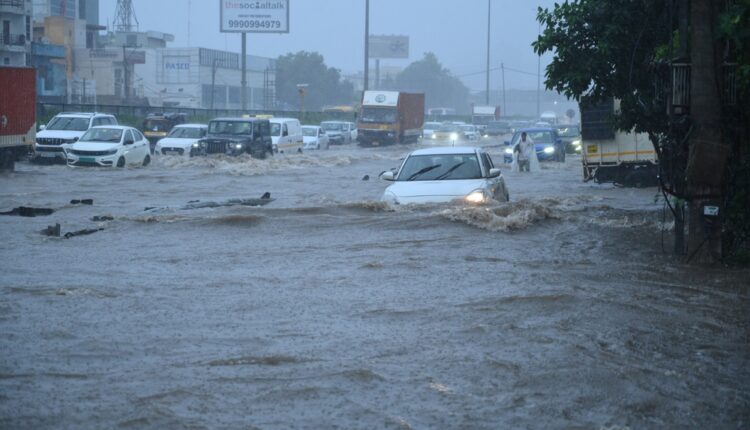 Cars driving through deep floodwater on a UAE city road during heavy rain, showing how UAE flood driving insurance claims can be affected when safety rules are ignored.