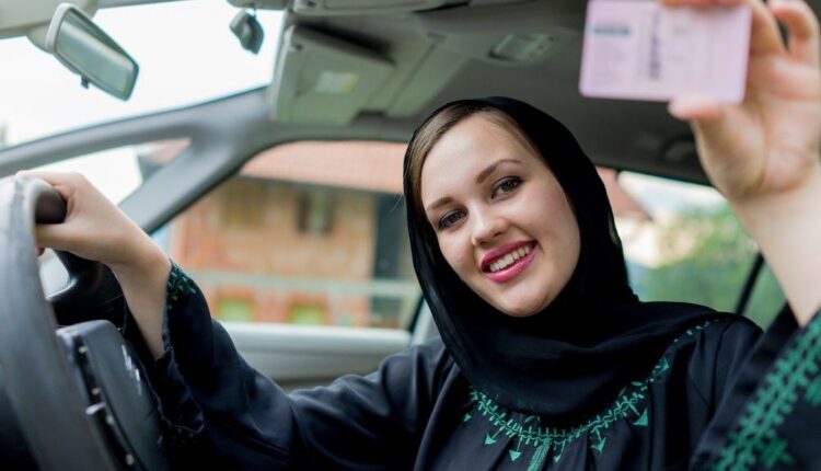A woman sitting inside her car in Dubai showing her driving licence, illustrating the process of converting a foreign driving licence in Dubai.