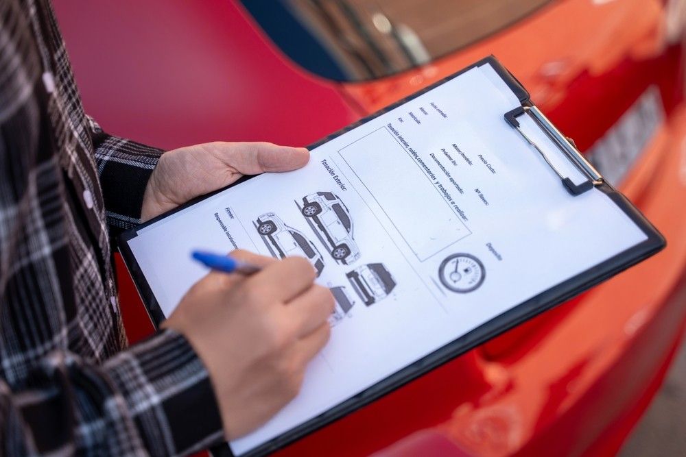 Insurance agent assessing car damage and filling claim form – UAE car insurance tips 2026