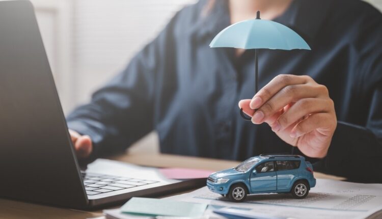 Man holding umbrella over toy car – symbolizing car insurance protection in UAE 2026