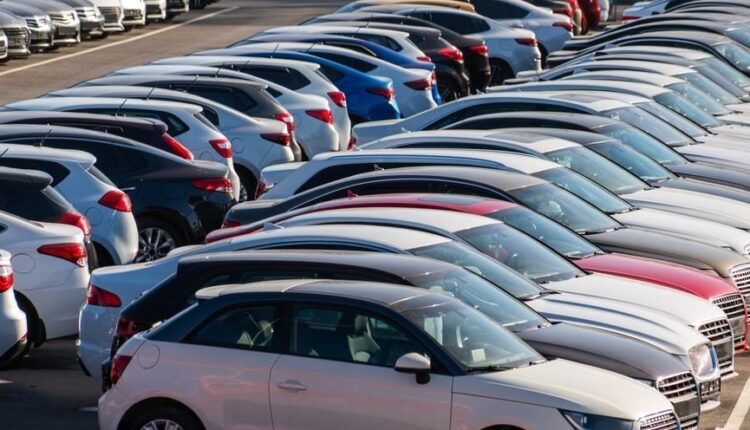 Rows of parked used cars in a dealership lot showing high supply and competition that can reduce resale value