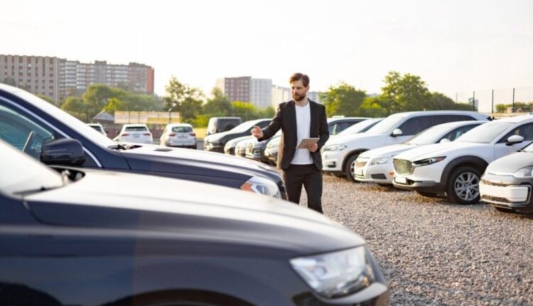 Buyer reviewing a used car at a dealership, evaluating different options in a spacious car lot, representing the process of researching and selecting the best deal.