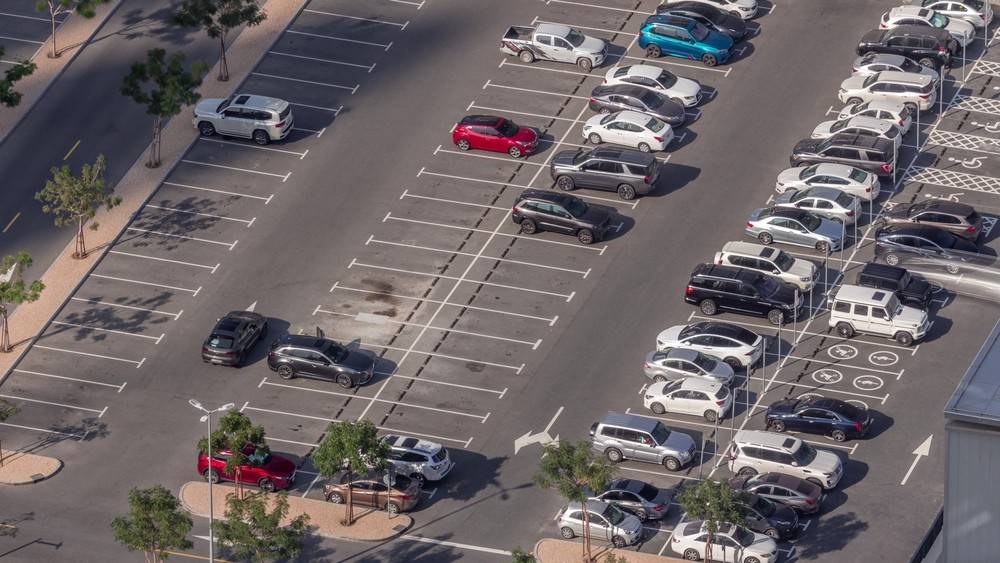 Aerial view of a well-organized parking lot in Dubai with cars parked in designated spaces, highlighting the importance of parking properly to avoid fines.