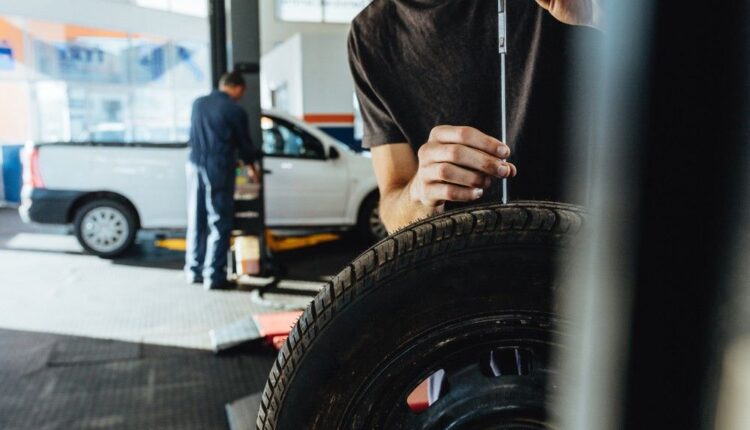 A technician inspecting a car in a workshop to check for wear and possible replacement helping determine when you need new tires.