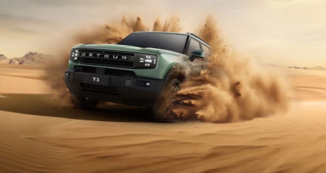 2026 Jetour T1 SUV driving through desert sand in the UAE, kicking up a large dust cloud during an off-road run.| Arabwheels.ae