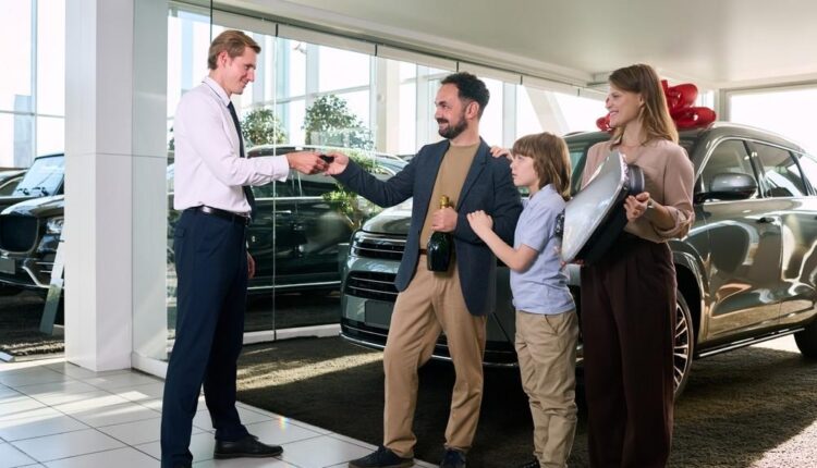 Family receiving car keys from a dealer inside a Dubai showroom after completing a used car sale.| Arabwheels.ae