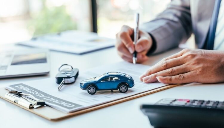 Car down payment in UAE explained with a buyer reviewing a car finance agreement, calculator, keys, and model car on the table.