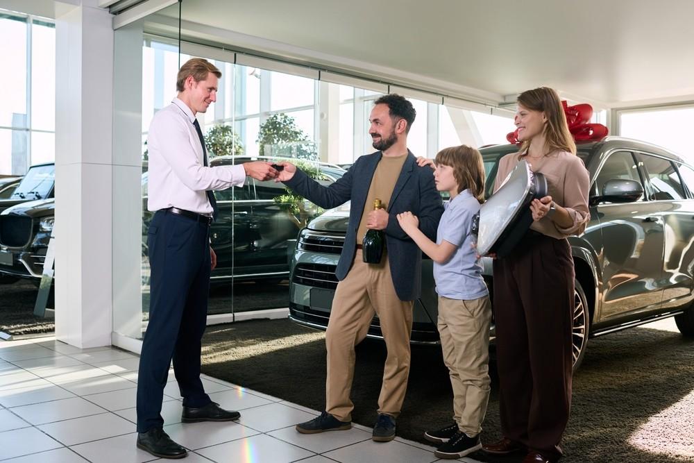 Family receiving car keys at a dealership after learning how to choose the right used car in UAE safely.| Arabwheels.ae