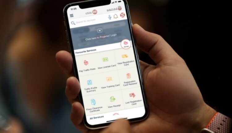 Checking EVG traffic fines online in the UAE using a smartphone inside a modern car.|Arabwheels.ae