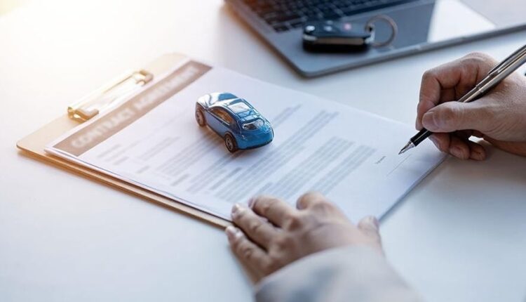 Car loan agreement documents with a miniature car model representing vehicle financing and ownership transfer process|Arabwheels.ae