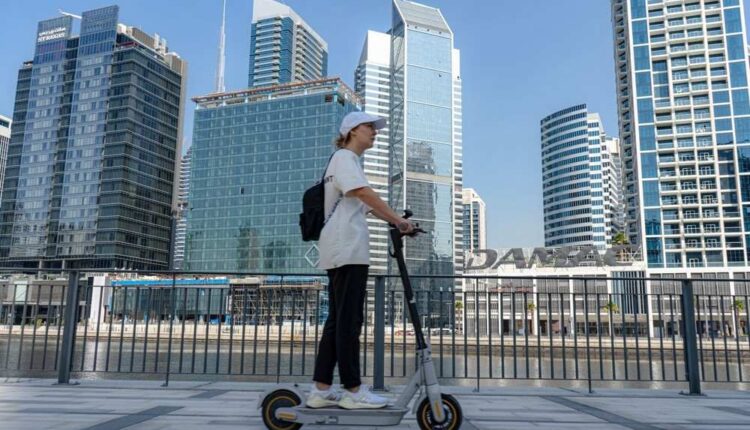 E-scooter rider in Dubai with city skyscrapers in the background|Arabwheels.ae