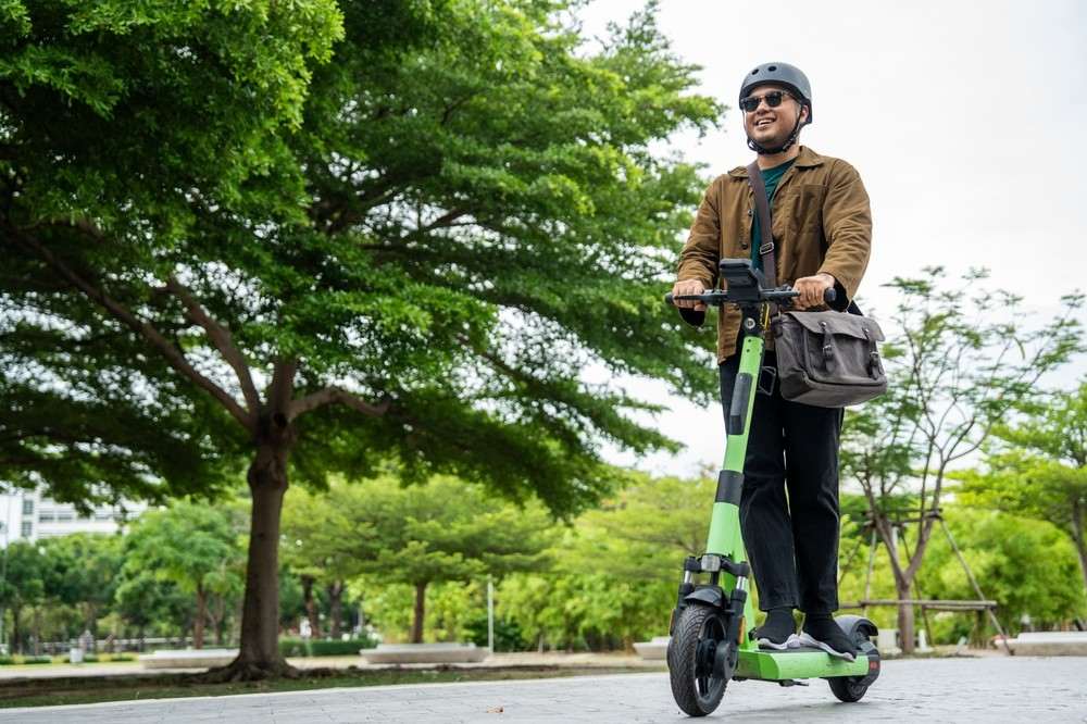 Man wearing a helmet while riding an electric scooter on a shared path|Arabwheels.ae