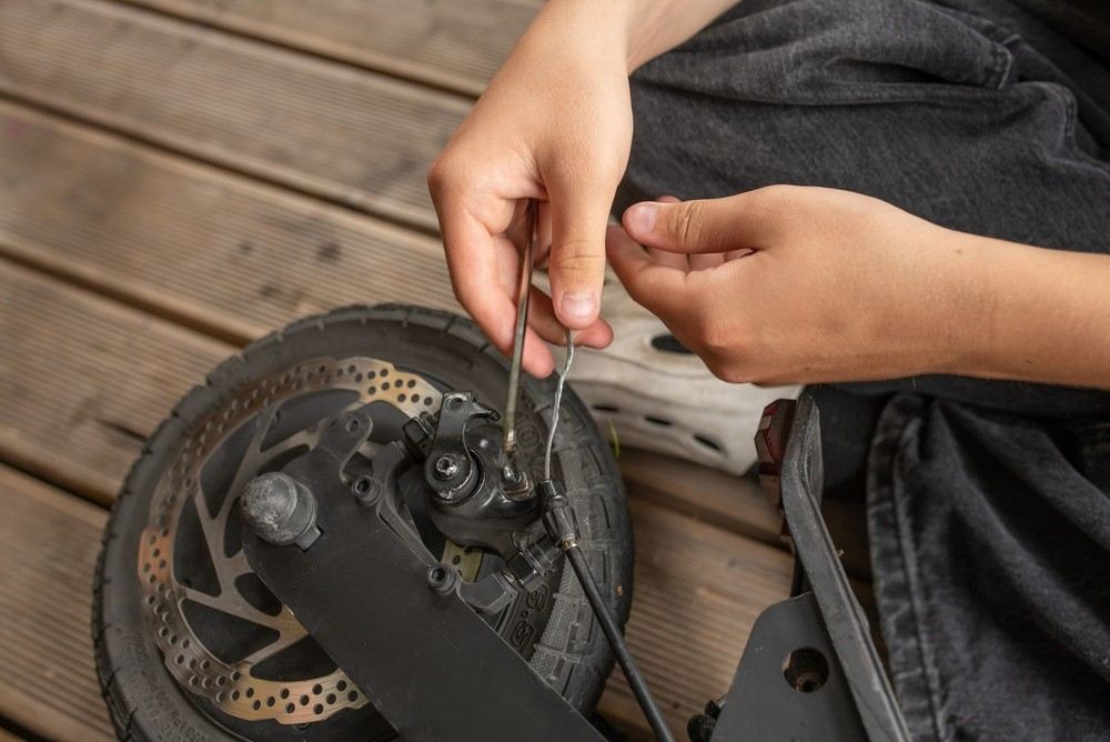 Person checking the brake system of an electric scooter|Arabwheels.ae