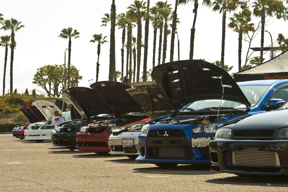 Modified Japanese performance cars lined up with open bonnets at a car meet|Arabwheels.ae